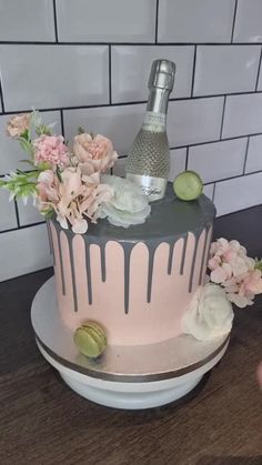 there is a cake with flowers and a bottle on the top it sits on a table