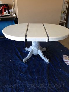 a white table sitting on top of a blue tarp covered floor next to a wall