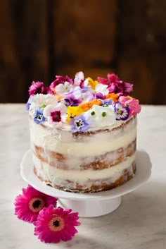 a cake with white frosting and colorful flowers on top