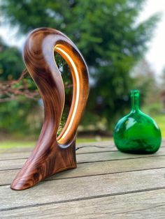 a green vase sitting on top of a wooden table next to a wood carving sculpture