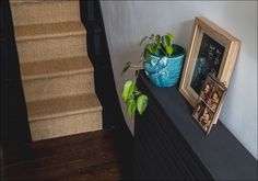 there is a plant on top of the dresser next to a framed photograph and an empty picture frame