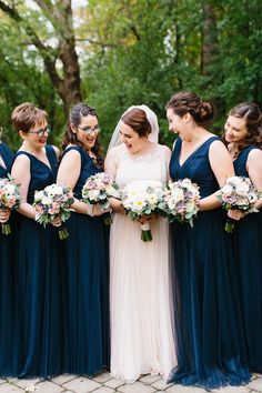 a group of women standing next to each other holding bouquets in their hands and smiling