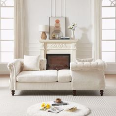 a living room filled with furniture and a fire place in front of two windows on either side of the couch