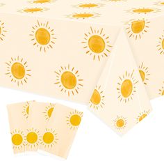 a table cloth with yellow sun designs on it and four napkins in front of it