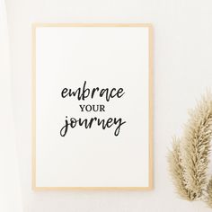 a framed print with the words embrace your journey on it next to some dried plants