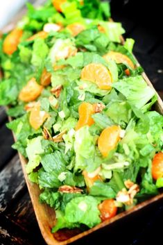 lettuce salad with oranges and almonds in a wooden tray on a table