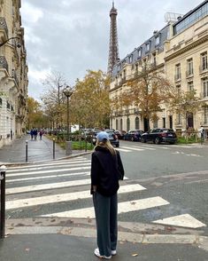 a woman standing in front of the eiffel tower with her back turned to the camera