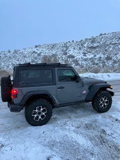 a gray jeep parked on the side of a snowy road