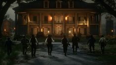 a group of people standing in front of a large house at night with lights on