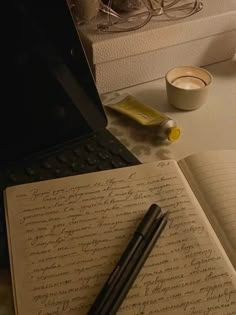 an open notebook sitting on top of a desk next to a laptop computer