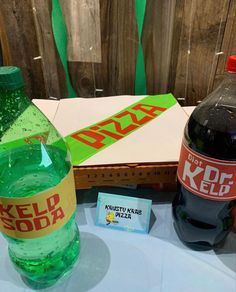 two bottles of soda sit next to each other on a table with a sign that says kddf