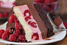 a piece of chocolate cake with raspberries on the side and one slice missing