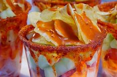 several glasses filled with food sitting on top of a white table covered in condiments