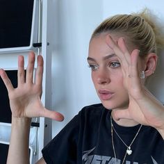 a woman holding her hands up in front of her face and making the vulcan sign