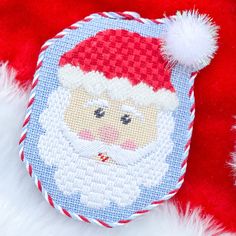 a cross stitch santa clause ornament on a red and white furnishing