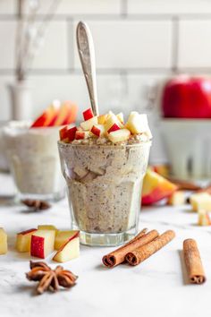 an apple cinnamon overnight oatmeal in a glass with apples and cinnamon on the side