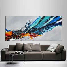 an abstract painting on the wall above a couch in a living room with white walls