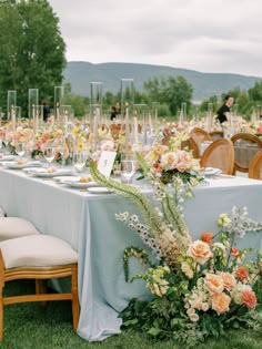 a table set up with flowers and place settings for an outdoor wedding reception in the mountains