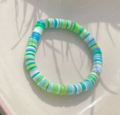 a close up of a bracelet on a white surface with green, blue and yellow stripes