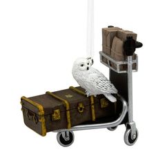 an owl sitting on top of a luggage cart next to a piece of brown luggage