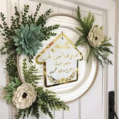 a wreath with flowers and greenery on it is hanging on the door to welcome guests