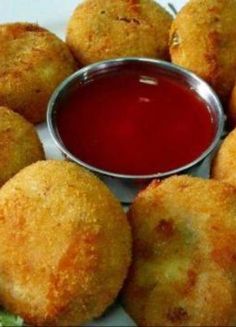 several fried food items on a plate with ketchup and dipping sauce in the middle