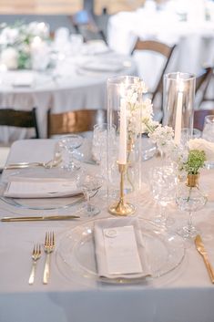 the table is set with silverware and white flowers