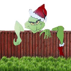 an image of a cartoon character in the grass wearing a santa hat and holding onto a fence