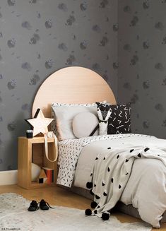 a bed with black and white pillows in a bedroom next to a star shaped night stand