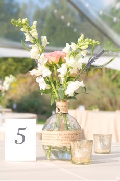 a vase filled with flowers sitting on top of a table next to two shot glasses