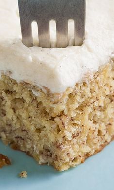 a piece of cake with white frosting and a fork stuck in the top slice