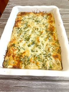 a casserole dish with cheese and broccoli in it on a wooden table