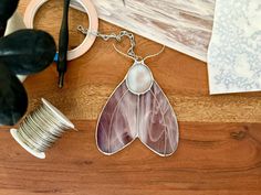 a close up of a necklace on a table with scissors and other items around it