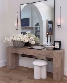 a wooden table topped with a mirror and vase filled with flowers