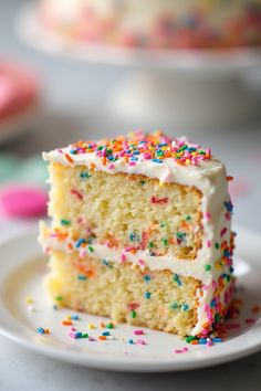 a slice of cake with white frosting and sprinkles on a plate