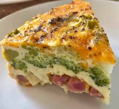 a piece of quiche with ham and cheese on a white plate, ready to be eaten