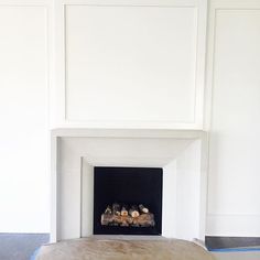 a fire place in the corner of a room with white walls and wood flooring