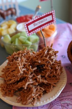 there are many different types of food on the plate and cupcakes in the background