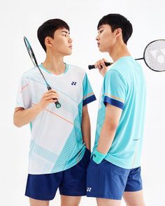 two young men standing next to each other holding tennis racquets