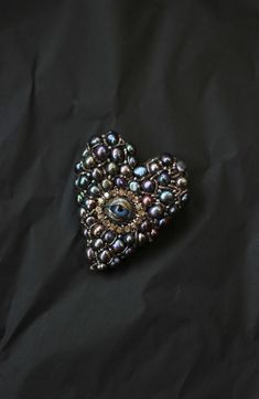 a heart shaped brooch sitting on top of a black cloth