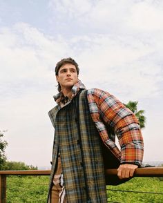 a man leaning on a fence with his hand on his hip and looking up at the sky