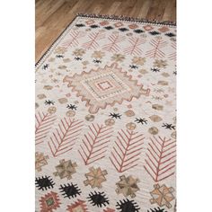 a white rug with black and red designs on the floor in front of a wooden floor