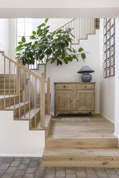 a room with stairs and a potted plant on the table in front of it