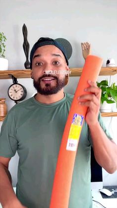 a man holding an orange object in front of his face and looking at the camera