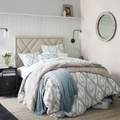 a bed with blue and white comforter in a bedroom next to a night stand