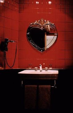 a red tiled bathroom with a sink and mirror in the corner, along with a phone