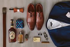 men's accessories laid out on a table including shoes, tie, and bottle