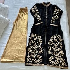 Palazzo Set. Black, Semi Georgette Kurta Top With Gold Zari And Gold Bras Work. Comes With A Gold Shimmer Bell Palazzo Pant. Black Sets With Gold Embroidery For Party, Black Party Sets With Gold Embroidery, Fitted Black Kurta With Gold Embroidery, Black Set With Gold Embroidery For Eid, Traditional Festive Workwear Sets, Black Long Sleeve Sets With Gold Embroidery, Elegant Black Long Sleeve Pant Set, Festive Black Bottoms, Traditional Gold Pants For Festive Occasion