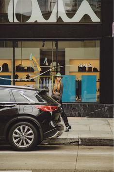 a woman sitting on the back of a car in front of a storefront window