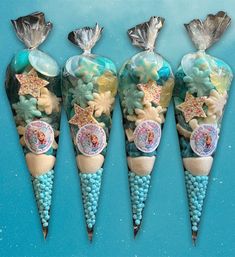 three cones filled with candy on top of a blue surface